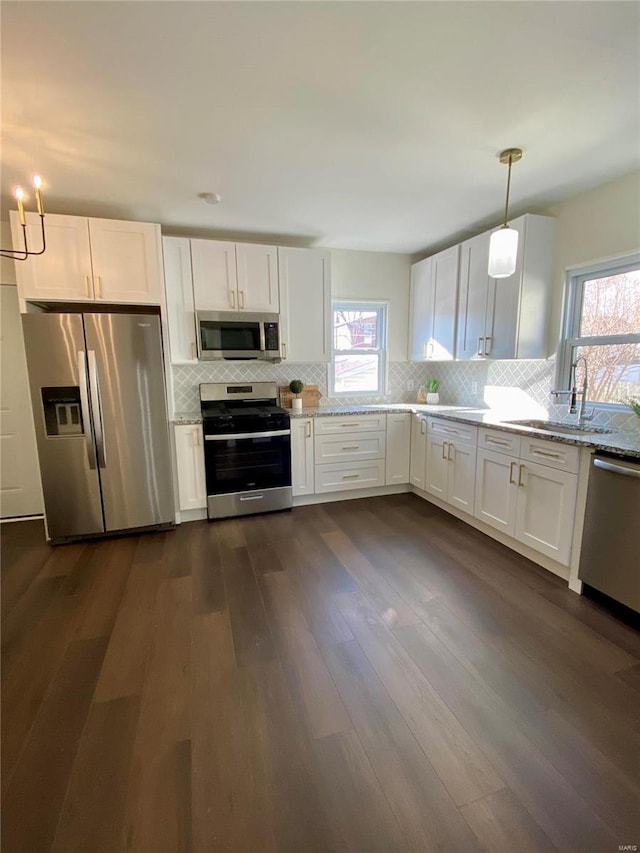 kitchen with stainless steel appliances, white cabinets, a sink, and backsplash