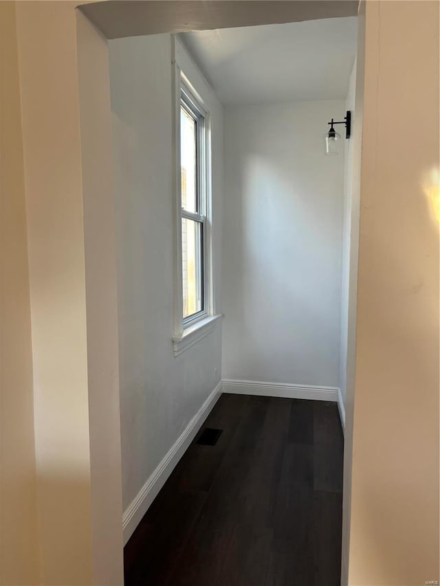 hallway featuring dark wood-style floors, visible vents, and baseboards