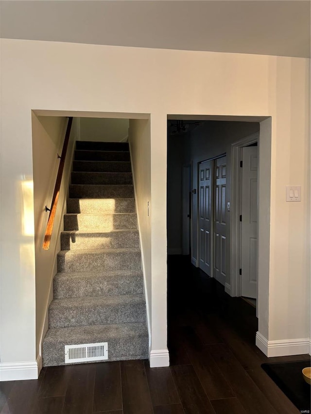 stairs featuring visible vents, baseboards, and wood finished floors