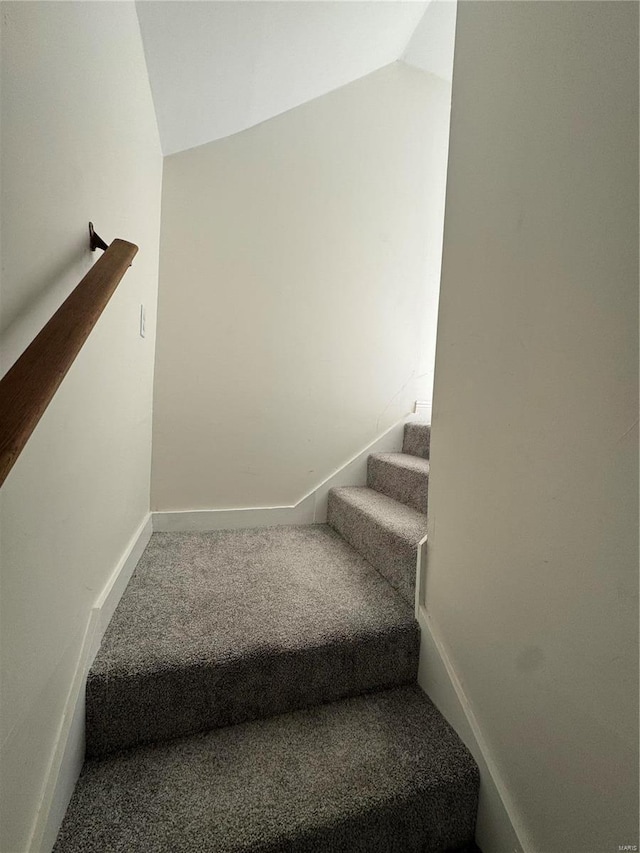 staircase with lofted ceiling, baseboards, and carpet