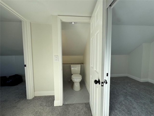 bathroom with toilet, vaulted ceiling, and tile walls