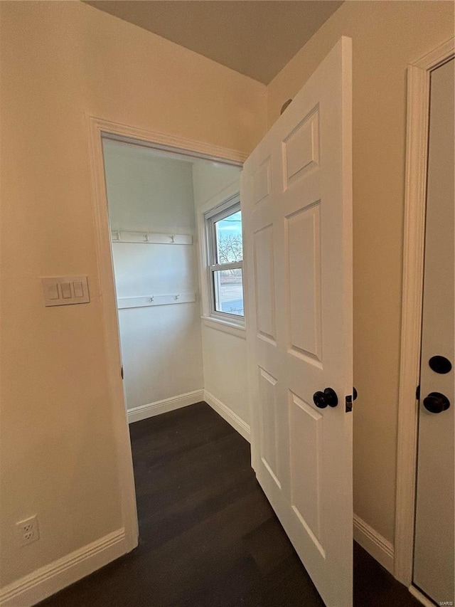 corridor featuring baseboards and dark wood-style flooring