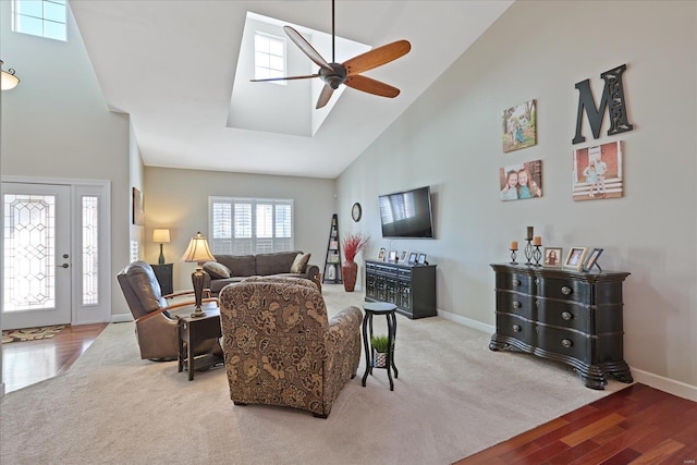 carpeted living area featuring baseboards, high vaulted ceiling, a ceiling fan, and wood finished floors