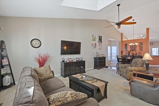 living room featuring light carpet, high vaulted ceiling, ceiling fan with notable chandelier, and baseboards