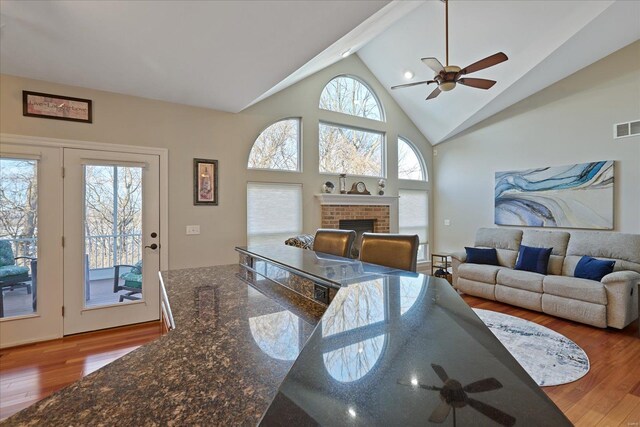 living room with a fireplace, visible vents, a ceiling fan, high vaulted ceiling, and hardwood / wood-style floors