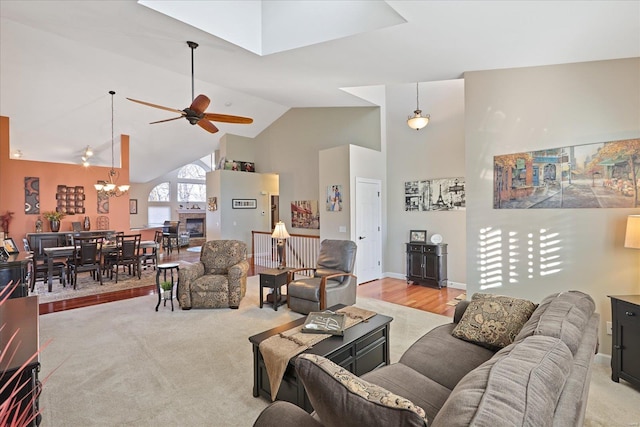 living area with light carpet, high vaulted ceiling, and ceiling fan with notable chandelier