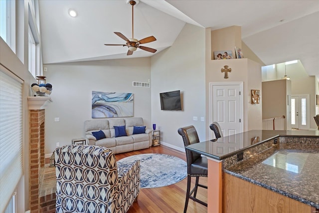 living area featuring baseboards, visible vents, high vaulted ceiling, and wood finished floors