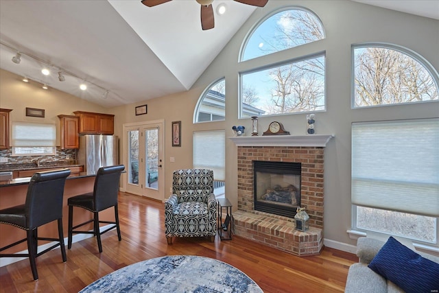 living area with high vaulted ceiling, wood finished floors, and a wealth of natural light