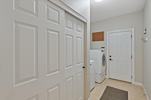 washroom featuring laundry area, washing machine and dryer, baseboards, and light tile patterned flooring