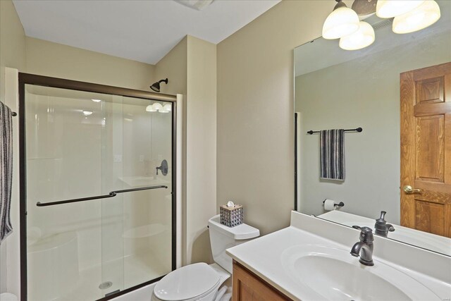 full bathroom featuring toilet, a shower stall, and vanity