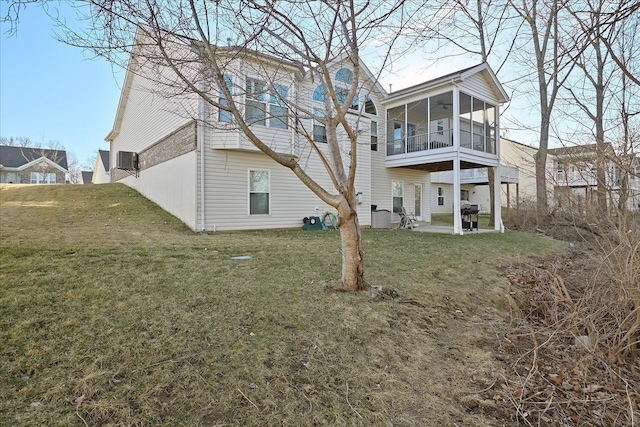 back of property with a sunroom, a patio area, and a yard