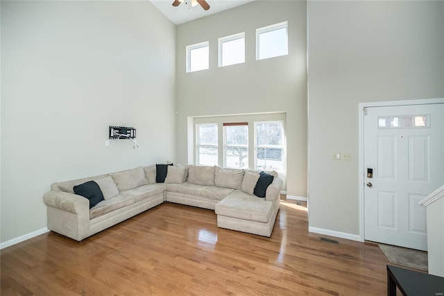 living room with light wood-type flooring, ceiling fan, and baseboards