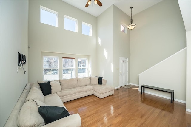 living area with baseboards, ceiling fan, and light wood finished floors