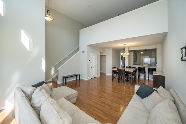 living room with baseboards, wood finished floors, stairs, a high ceiling, and a chandelier