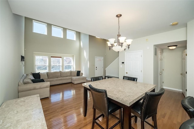 dining room with a chandelier, a high ceiling, wood finished floors, and baseboards