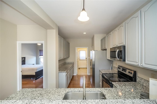 kitchen featuring light stone countertops, appliances with stainless steel finishes, dark wood-style flooring, and a sink