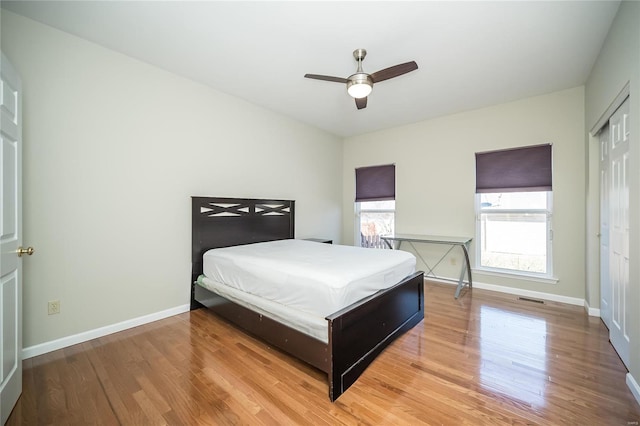 bedroom featuring ceiling fan, wood finished floors, visible vents, and baseboards