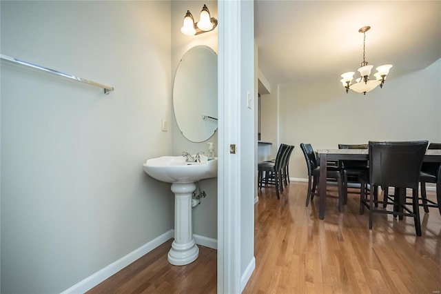 bathroom featuring an inviting chandelier, baseboards, and wood finished floors