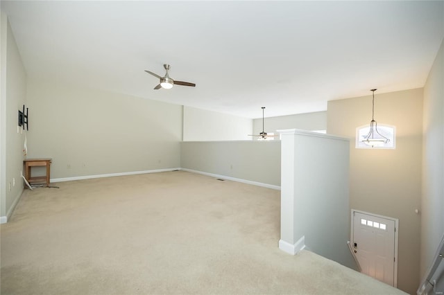 interior space with light colored carpet, ceiling fan, and baseboards