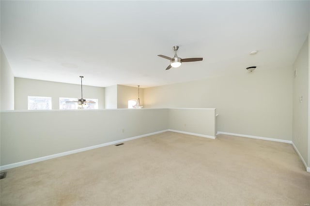 empty room featuring a ceiling fan, light carpet, visible vents, and baseboards