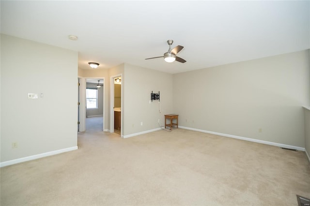 spare room with light carpet, baseboards, and a ceiling fan