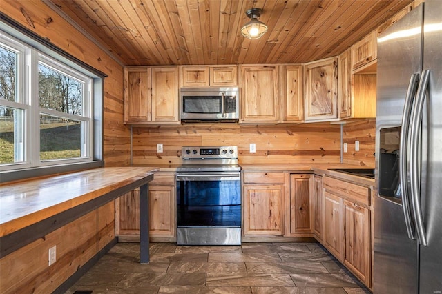 kitchen with wooden walls, wooden ceiling, wood counters, stainless steel appliances, and light brown cabinetry