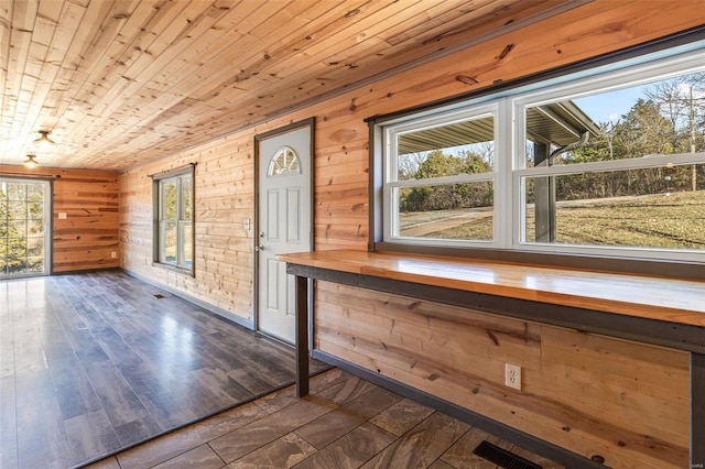 interior space featuring dark wood-type flooring, wooden ceiling, visible vents, and wooden walls