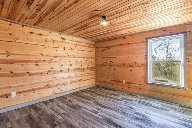 empty room with wood walls, wooden ceiling, wood finished floors, and visible vents