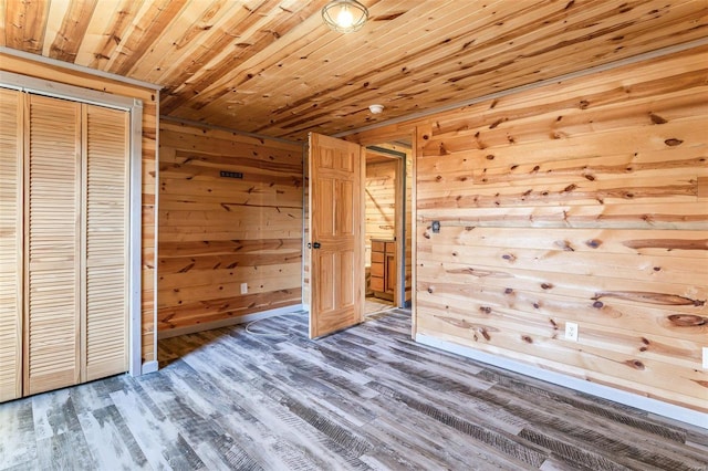 unfurnished bedroom featuring wood walls, wood ceiling, a closet, and wood finished floors