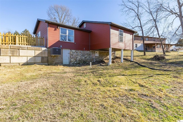 rear view of house featuring stone siding and a lawn