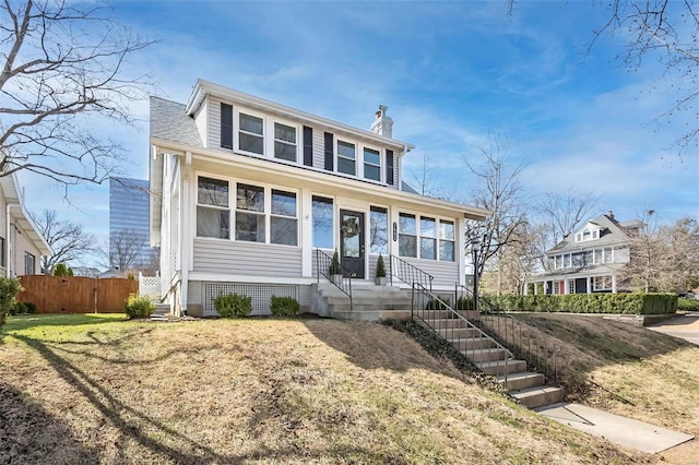 view of front of home with entry steps, a chimney, and fence