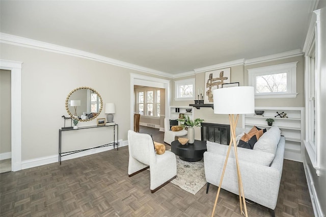 living room featuring plenty of natural light, baseboards, crown molding, and a glass covered fireplace