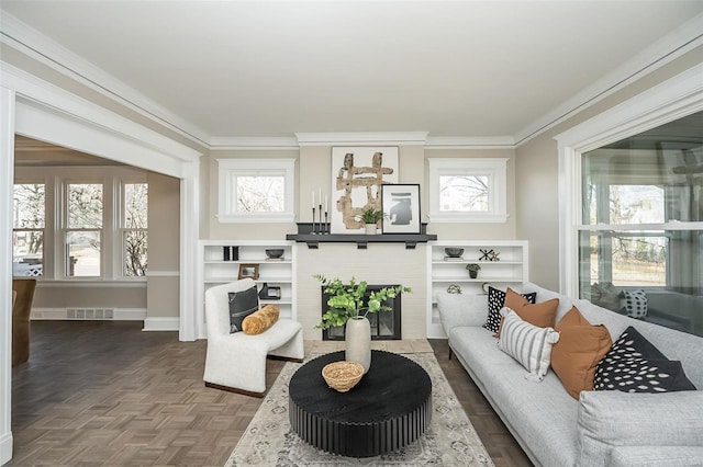 living area with baseboards, visible vents, and crown molding