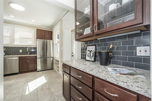 kitchen with dark brown cabinetry, tasteful backsplash, glass insert cabinets, light stone counters, and stainless steel appliances