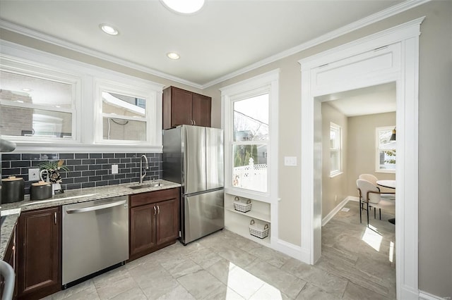 kitchen with a sink, light stone countertops, stainless steel appliances, crown molding, and backsplash