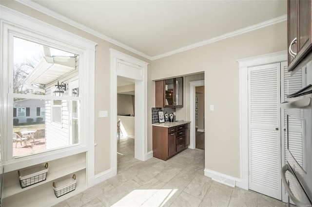 kitchen with dark brown cabinetry, baseboards, and ornamental molding