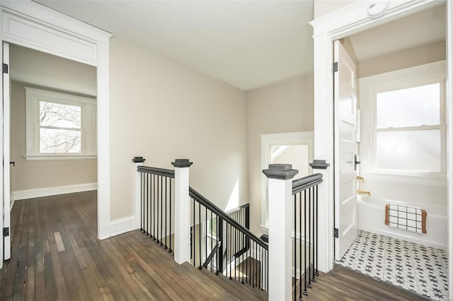 corridor with baseboards, dark wood-style flooring, and an upstairs landing