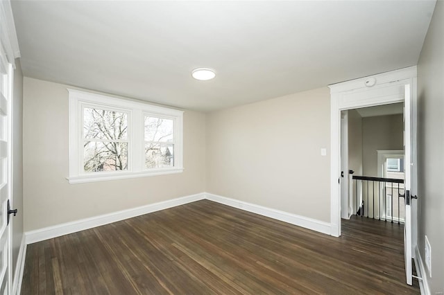 unfurnished room with dark wood-style floors and baseboards