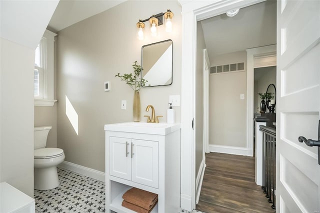 bathroom featuring baseboards, visible vents, vanity, and toilet