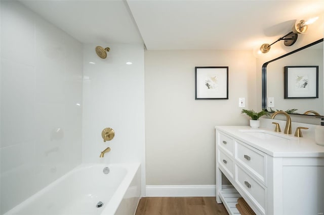 bathroom featuring baseboards, tub / shower combination, wood finished floors, and vanity