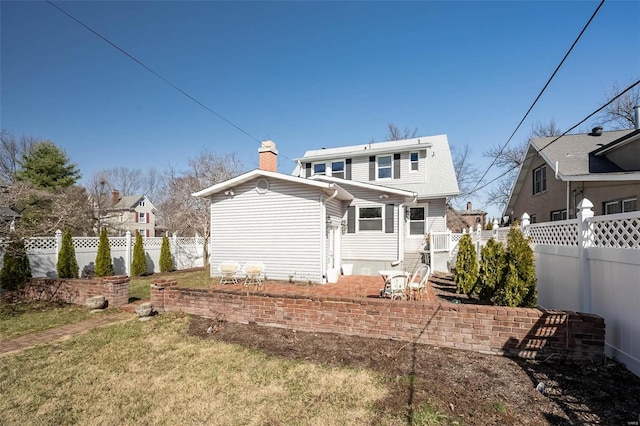 rear view of house with a chimney and a fenced backyard