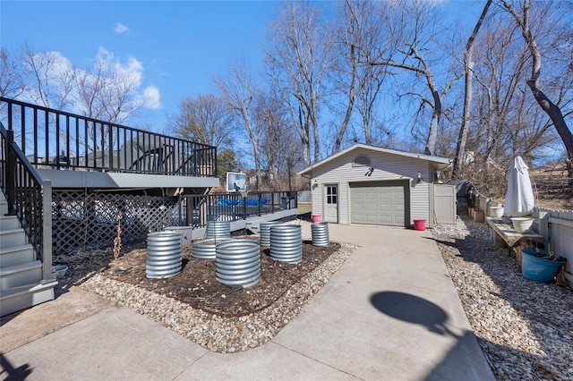 exterior space featuring an outbuilding, a deck, a detached garage, stairs, and concrete driveway