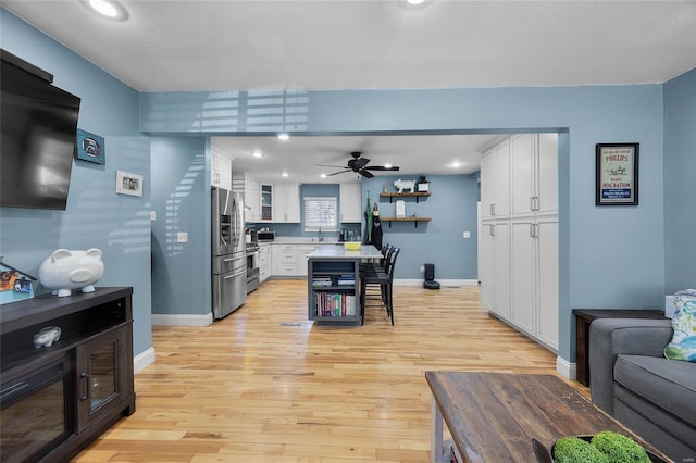 kitchen with open shelves, light countertops, light wood-style flooring, white cabinets, and stainless steel fridge