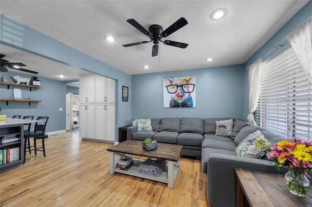 living area featuring baseboards, light wood finished floors, a ceiling fan, and recessed lighting