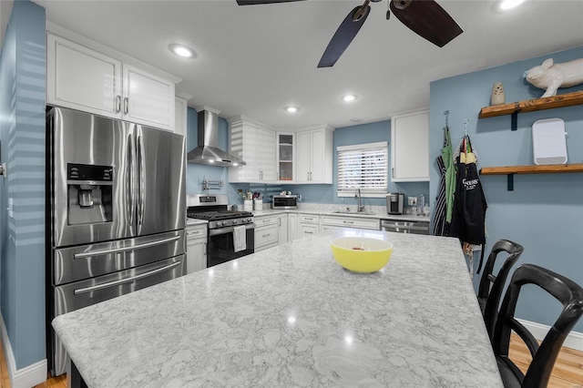 kitchen featuring white cabinets, wall chimney exhaust hood, stainless steel appliances, and a sink