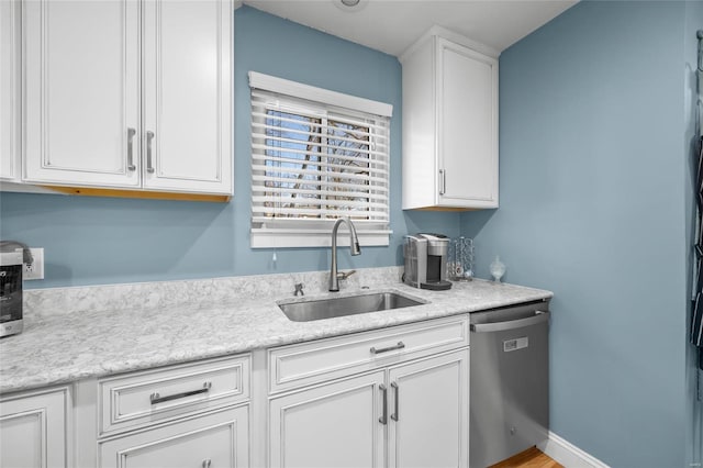 kitchen featuring a sink, baseboards, white cabinetry, and stainless steel dishwasher