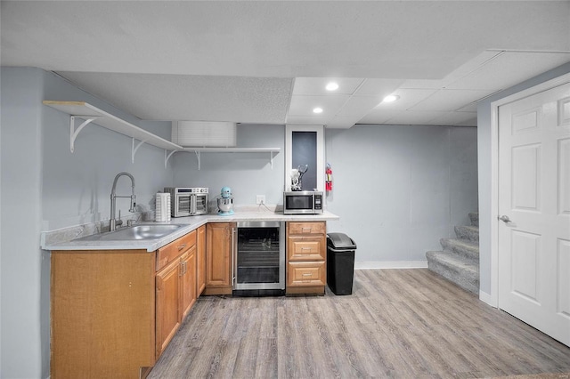 bar featuring wine cooler, a sink, baseboards, light wood finished floors, and stainless steel microwave