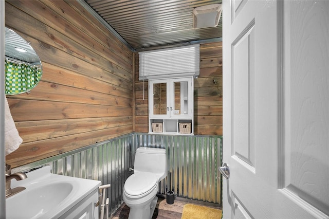 bathroom with wood walls, vanity, and toilet