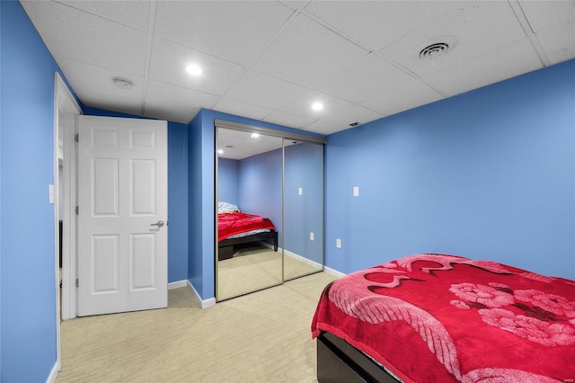 bedroom with a closet, visible vents, a drop ceiling, and baseboards