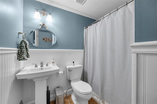 bathroom with toilet, a wainscoted wall, visible vents, and crown molding